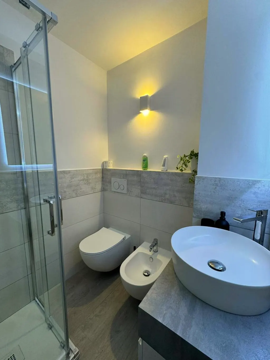 Sanitari sospesi e lavabo bianco su piano in pietra grigia